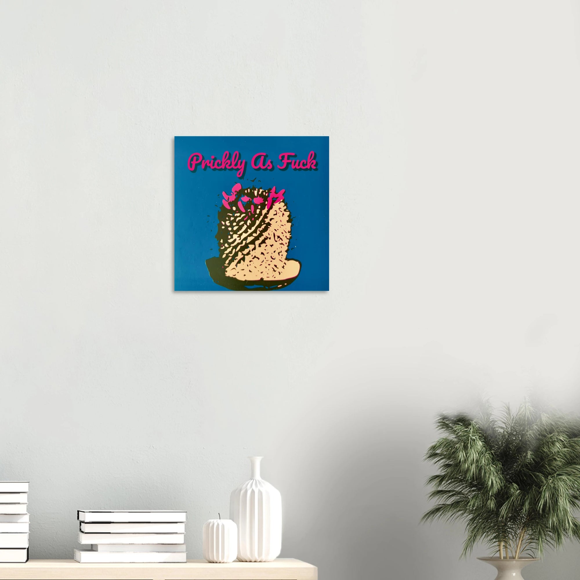 Prickly As Fuck cactus print on textured dark wall above white sofa